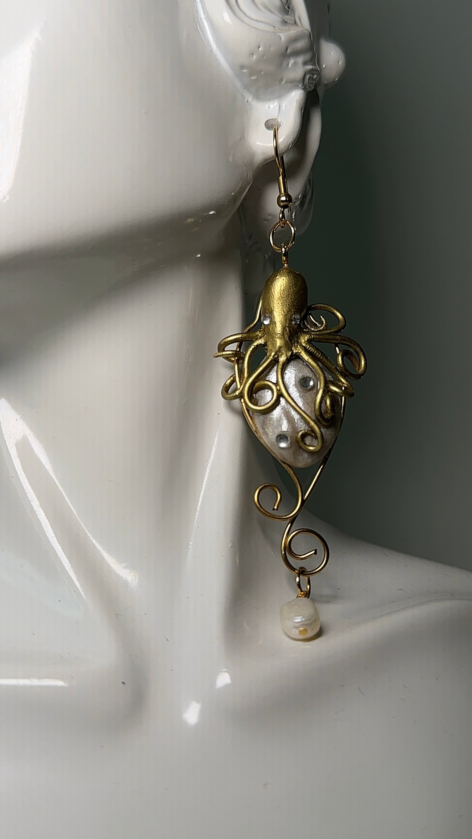 Close-up of unique marine-themed earrings in gold and ivory tones, sculpted and assembled by hand with stainless steel hooks.