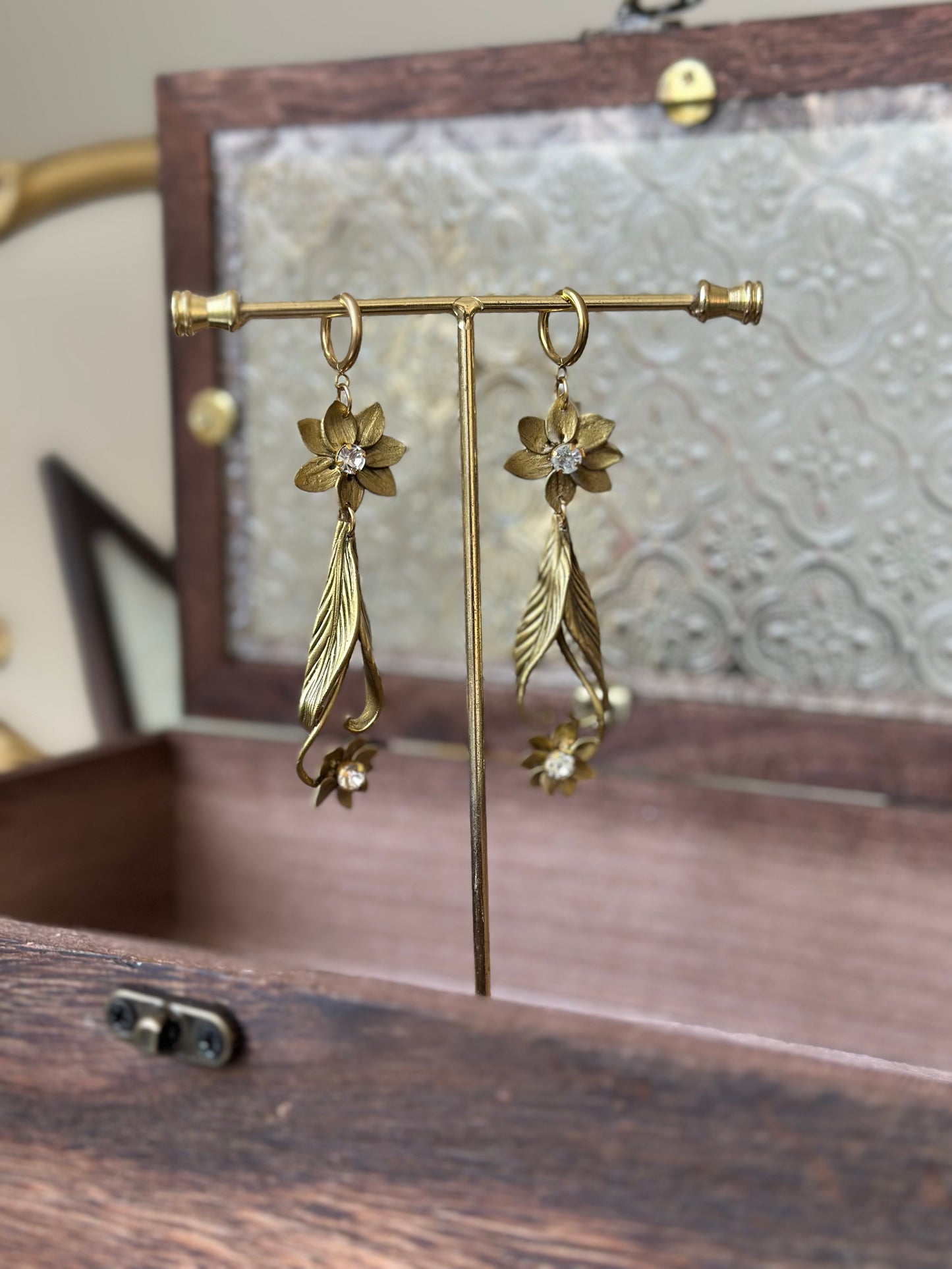 Golden stainless steel earrings with intricate petals and zirconia accents, presented as collectible jewelry.