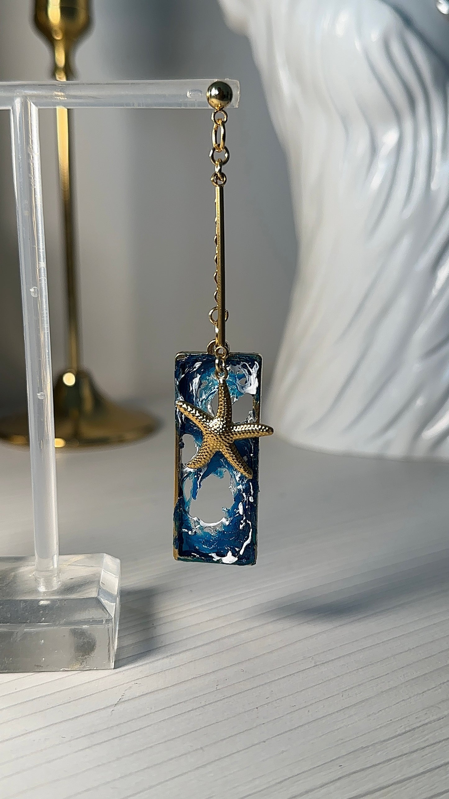 Ocean dream earrings with sculpted waves and golden sea creatures, captured in intimate lighting