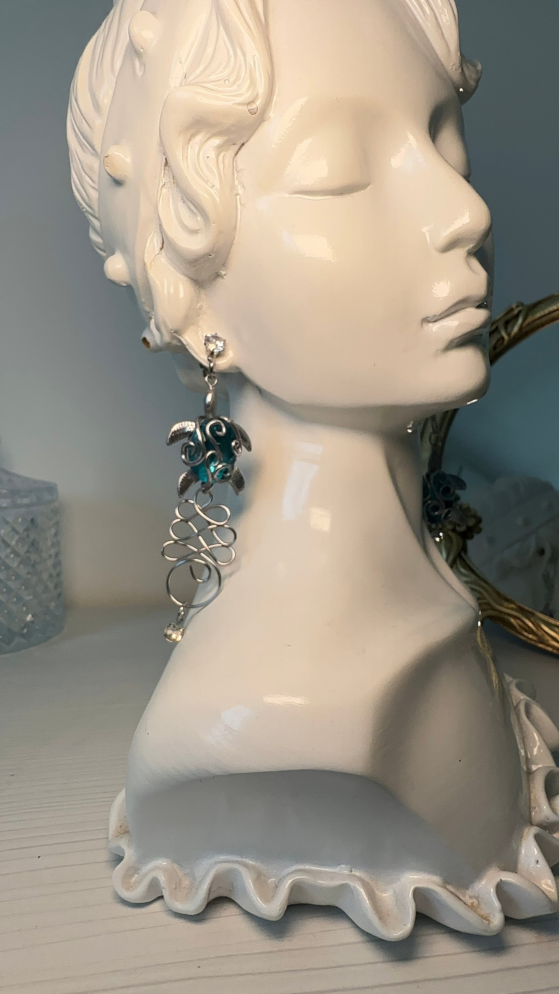 Handcrafted statement earrings inspired by sea life, with asymmetrical design and metallic turtle elements.