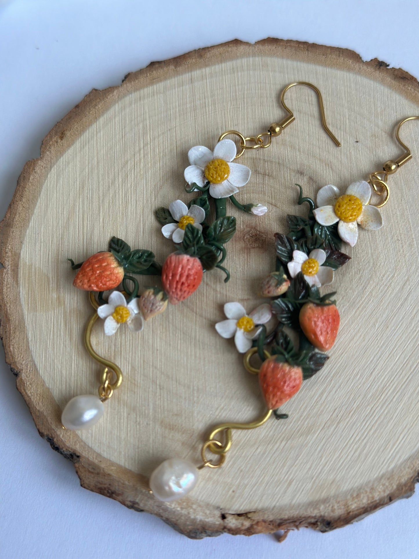 Orecchino artigianale in pasta polimerica con fragole, fiori bianchi, filo dorato e perla. Gioiello botanico romantico.
Handmade polymer clay earring with strawberries, white flowers, gold wire, and pearl. Botanical romantic jewelry.