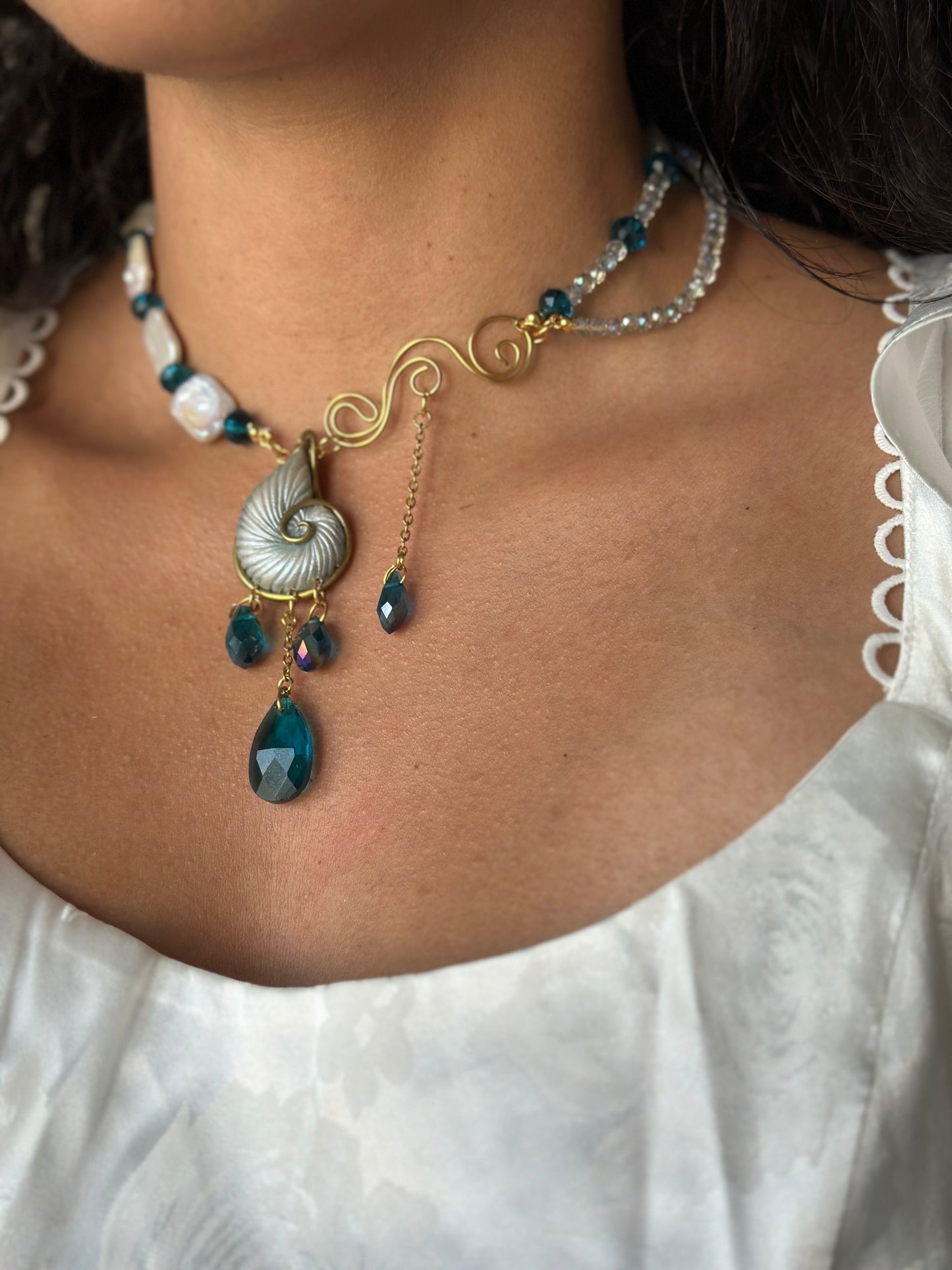 Elegant nautical necklace with gold wire detailing and ocean blue gemstone accents.