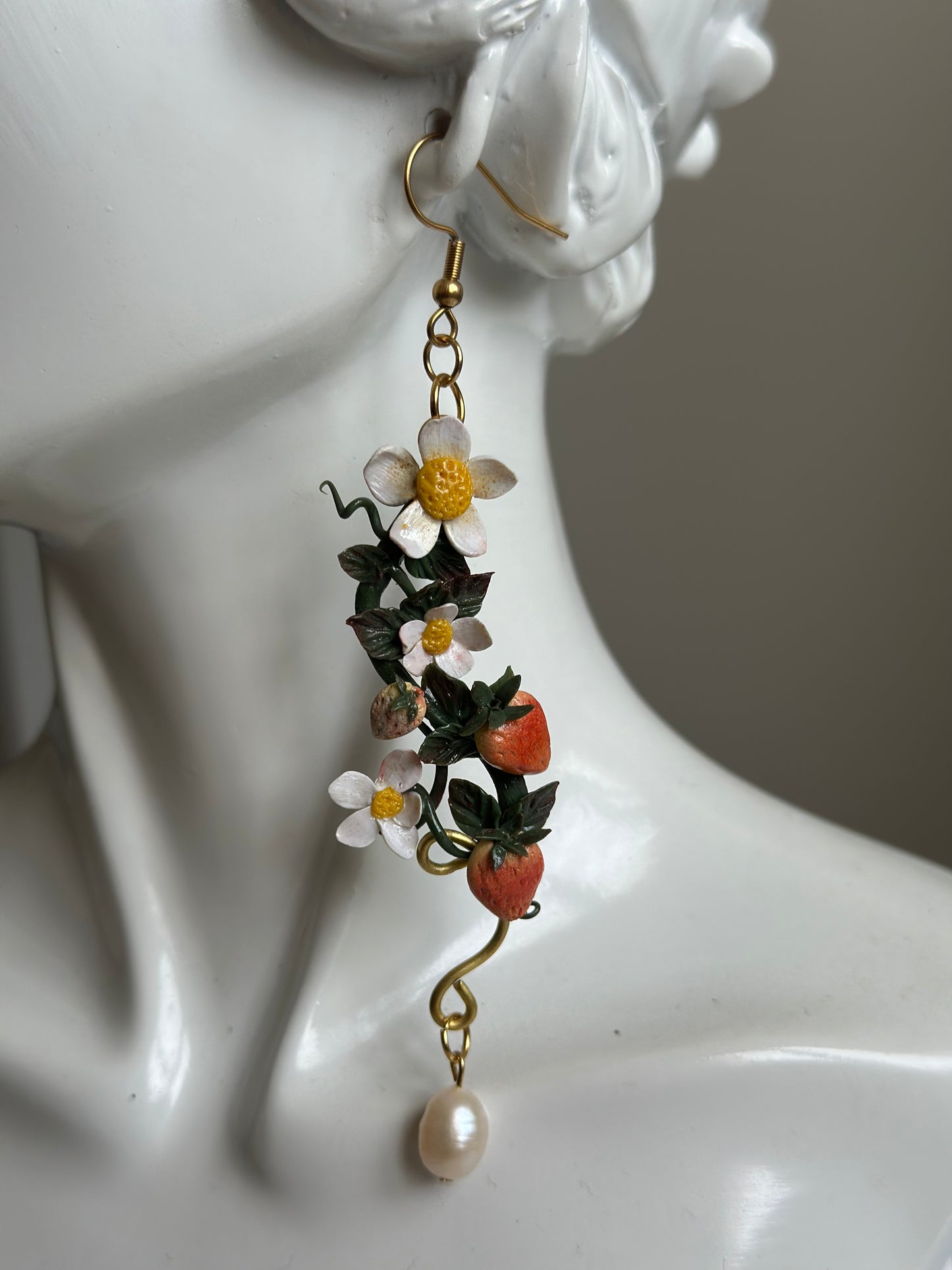 Model wearing handmade strawberry and flower polymer clay earring with pearl accent.