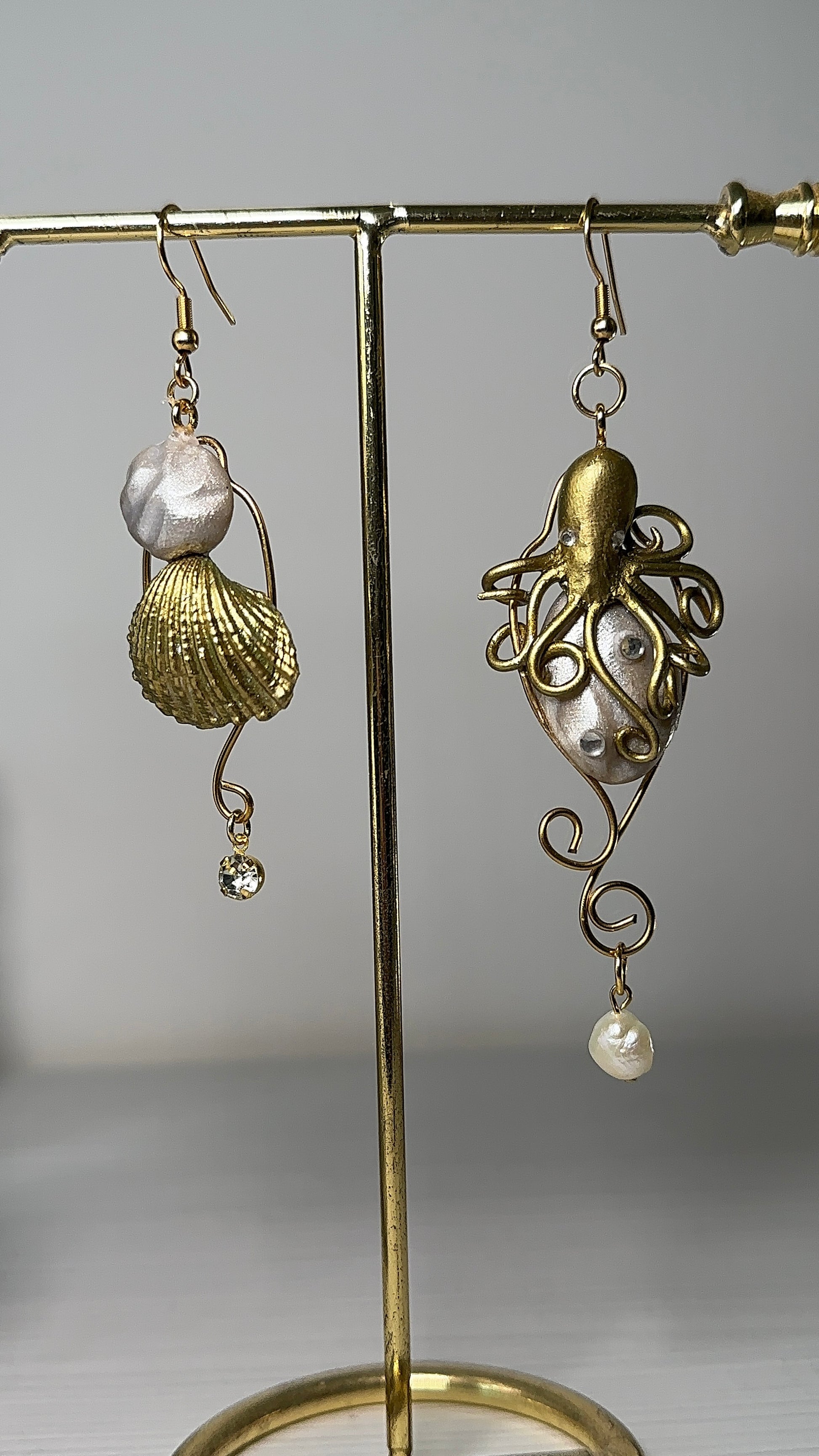 One-of-a-kind asymmetrical earrings with sculpted sea motifs, featuring swirling tentacles and natural pearl drops.