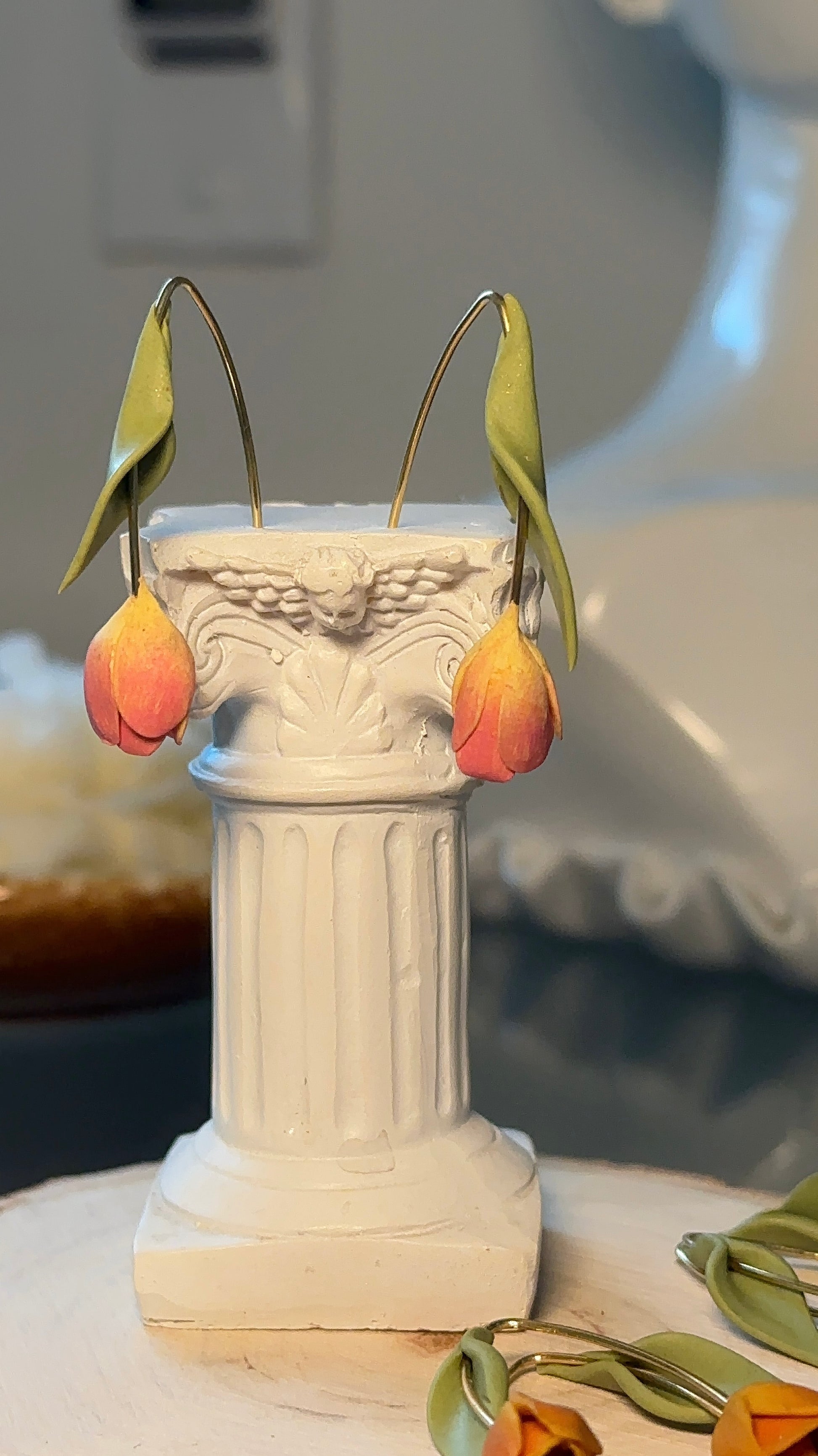 Tulip-shaped earrings placed on vintage fabric – artisan jewelry with soft botanical tones.