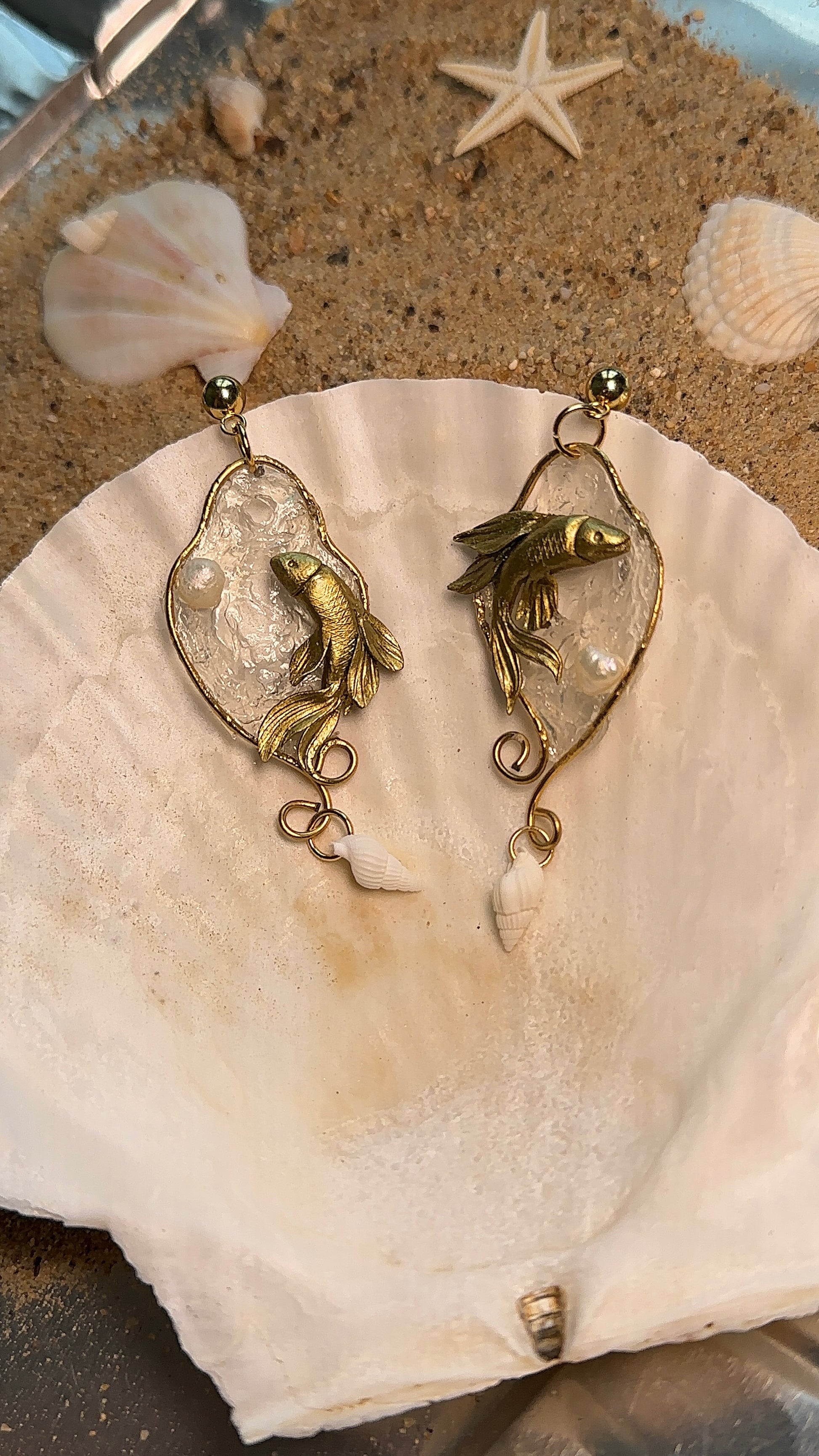 Unique ocean-themed earrings with swirling golden fish inside a sculptural aquatic scene, handmade in polymer clay.