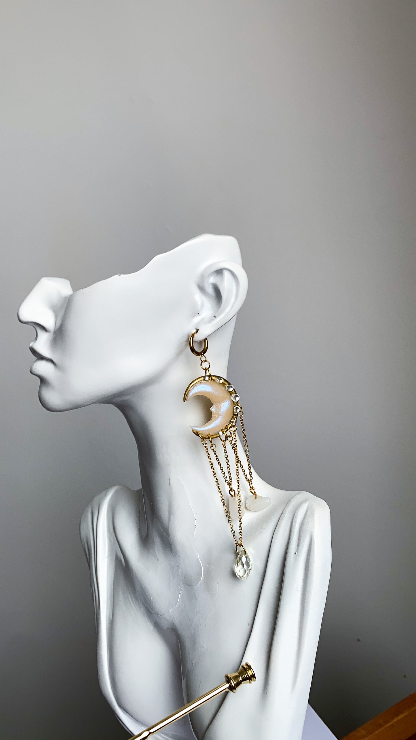 Close-up of celestial crescent moon earrings with dangling crystals, shimmering in soft natural light.