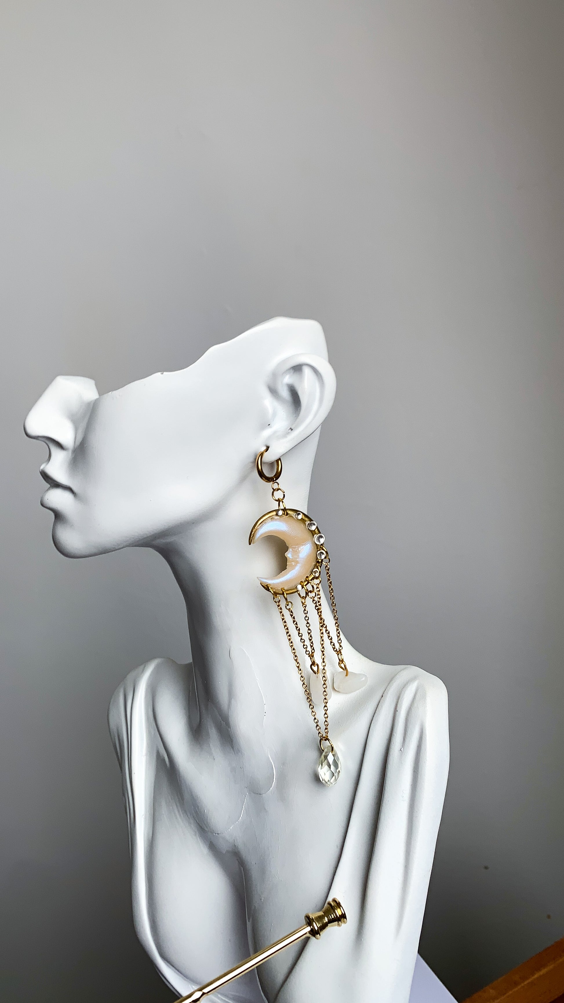 Close-up of celestial crescent moon earrings with dangling crystals, shimmering in soft natural light.