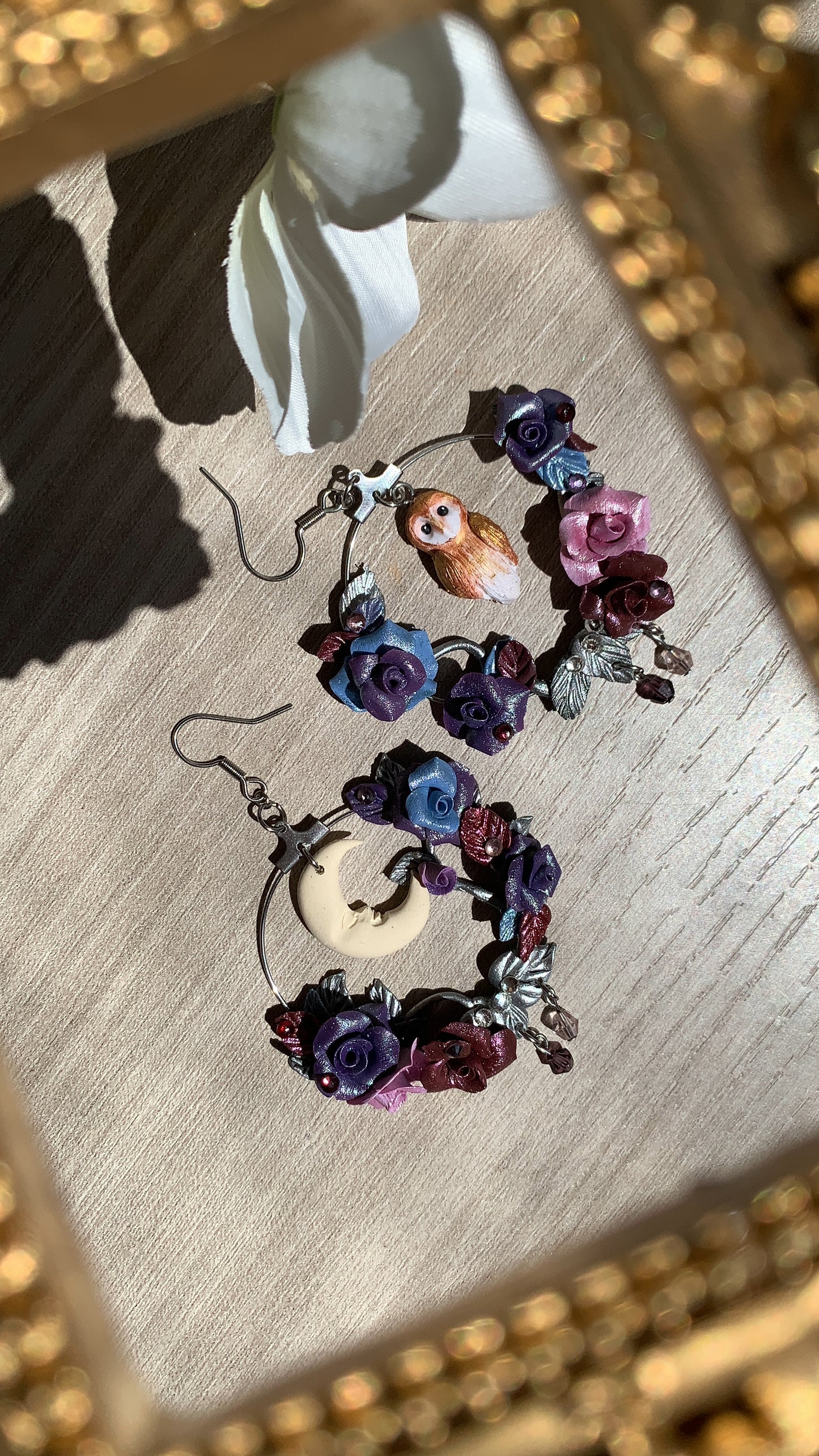 Hand-sculpted hoop earrings with a tiny owl and roses in purple and burgundy shades, set around a crescent moon.