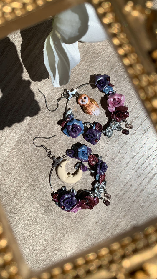 Hand-sculpted hoop earrings with a tiny owl and roses in purple and burgundy shades, set around a crescent moon.