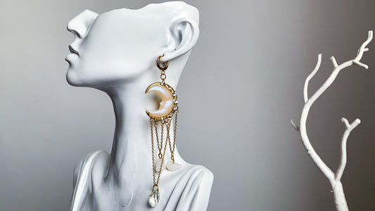 Elegant handmade moon earrings with golden chains and crystal drops, photographed on a classical white bust.