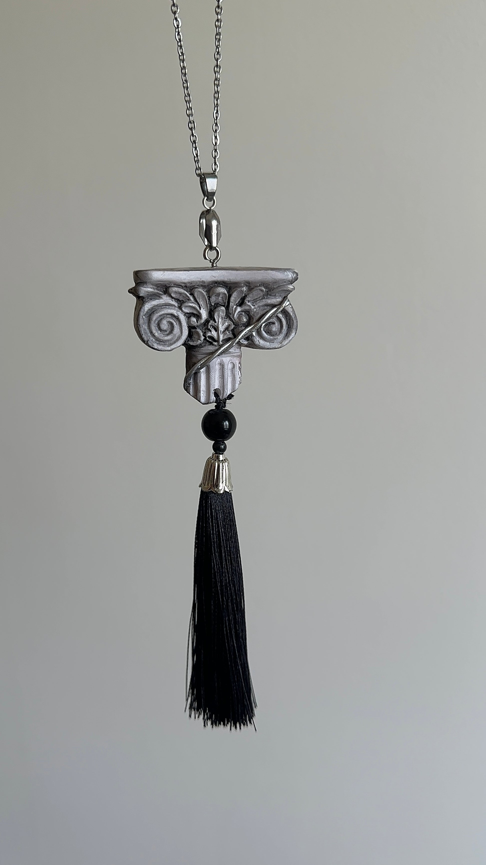     Handmade architectural tassel necklace with sculptural column pendant, black tassel and dark bead for dramatic refined outfits.