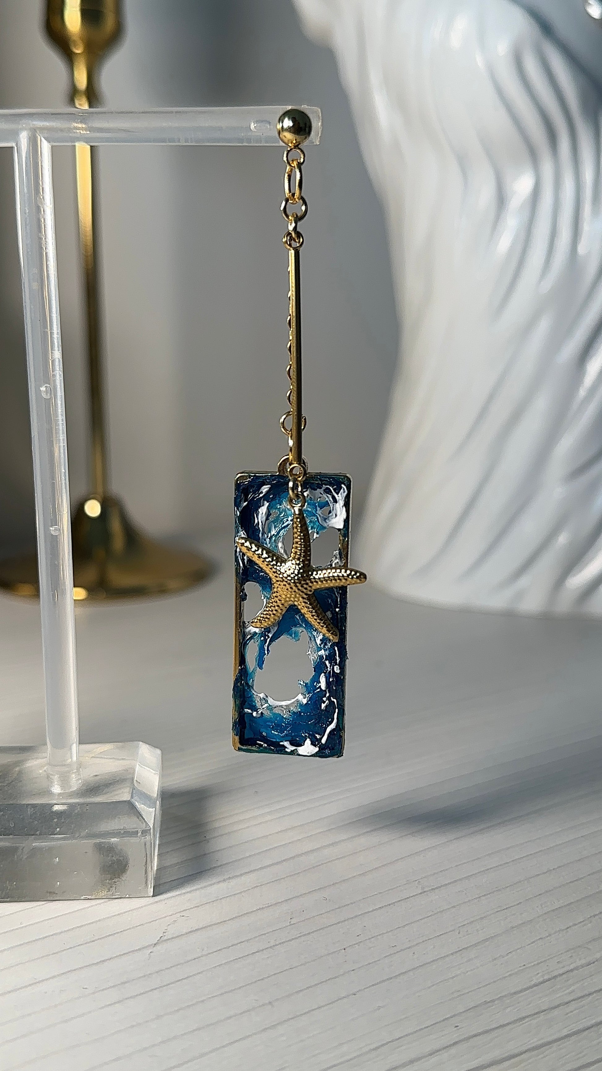 Ocean dream earrings with sculpted waves and golden sea creatures, captured in intimate lighting