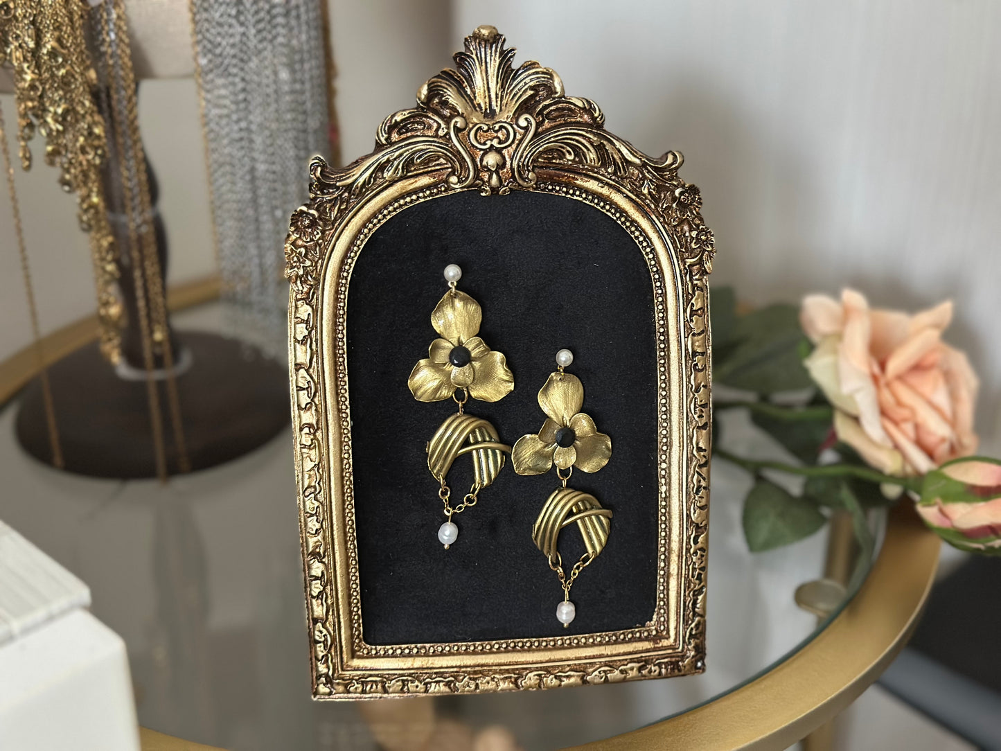 Orecchini floreali dorati artigianali con archi metallici curvi e perle pendenti, realizzati con cura scultorea.
