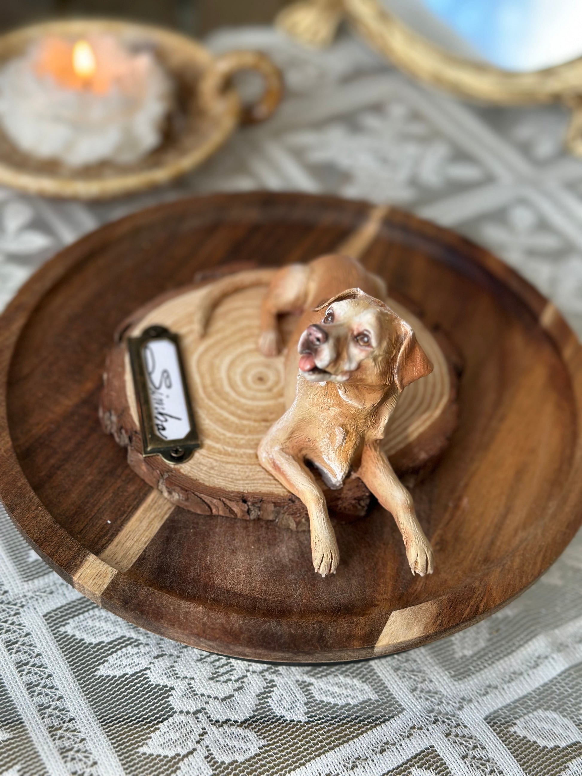 Realistic miniature dog sculpture standing on a carved wooden base with nameplate, surrounded by warm décor and soft florals. A timeless memorial piece for those who want to honor a cherished companion with elegance and tenderness.
