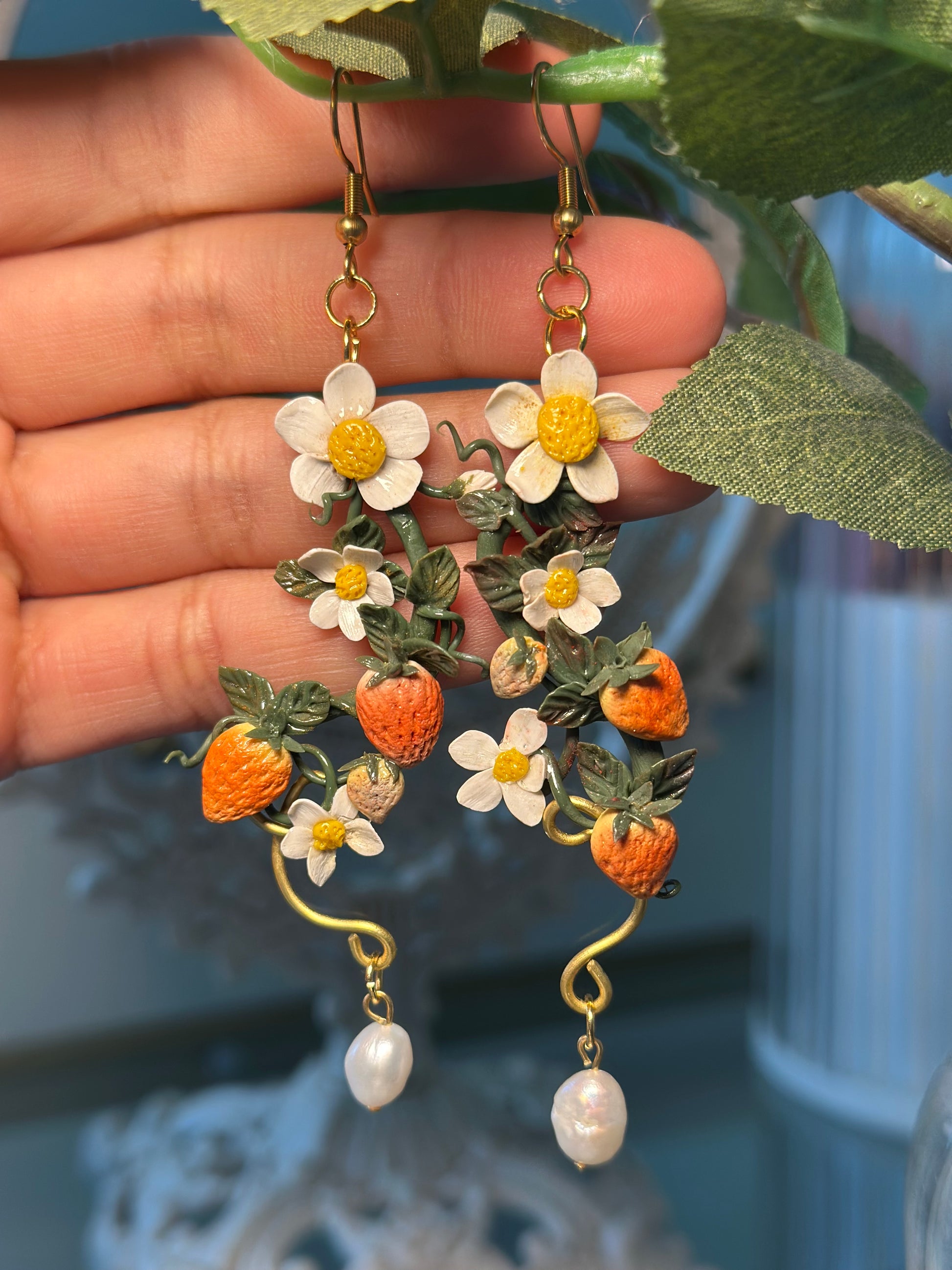 Orecchino artigianale in pasta polimerica con fragole, fiori bianchi, filo dorato e perla. Gioiello botanico romantico.
Handmade polymer clay earring with strawberries, white flowers, gold wire, and pearl. Botanical romantic jewelry.
