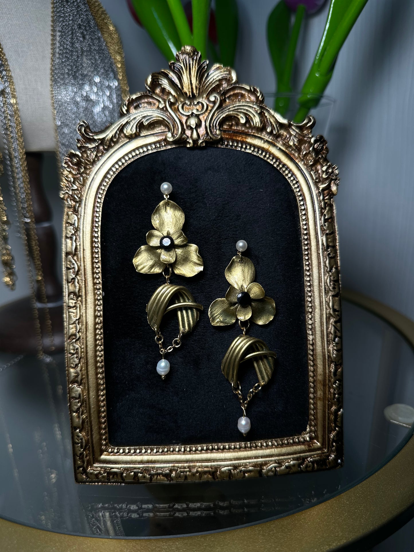 Luxurious floral earrings in gold and pearl, with asymmetrical design and baroque inspiration, photographed for a product showcase.