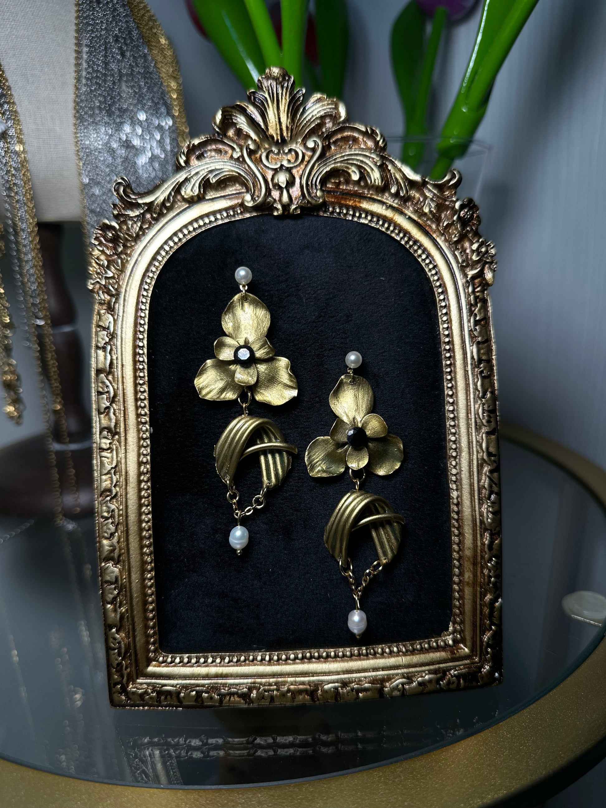 Luxurious floral earrings in gold and pearl, with asymmetrical design and baroque inspiration, photographed for a product showcase.