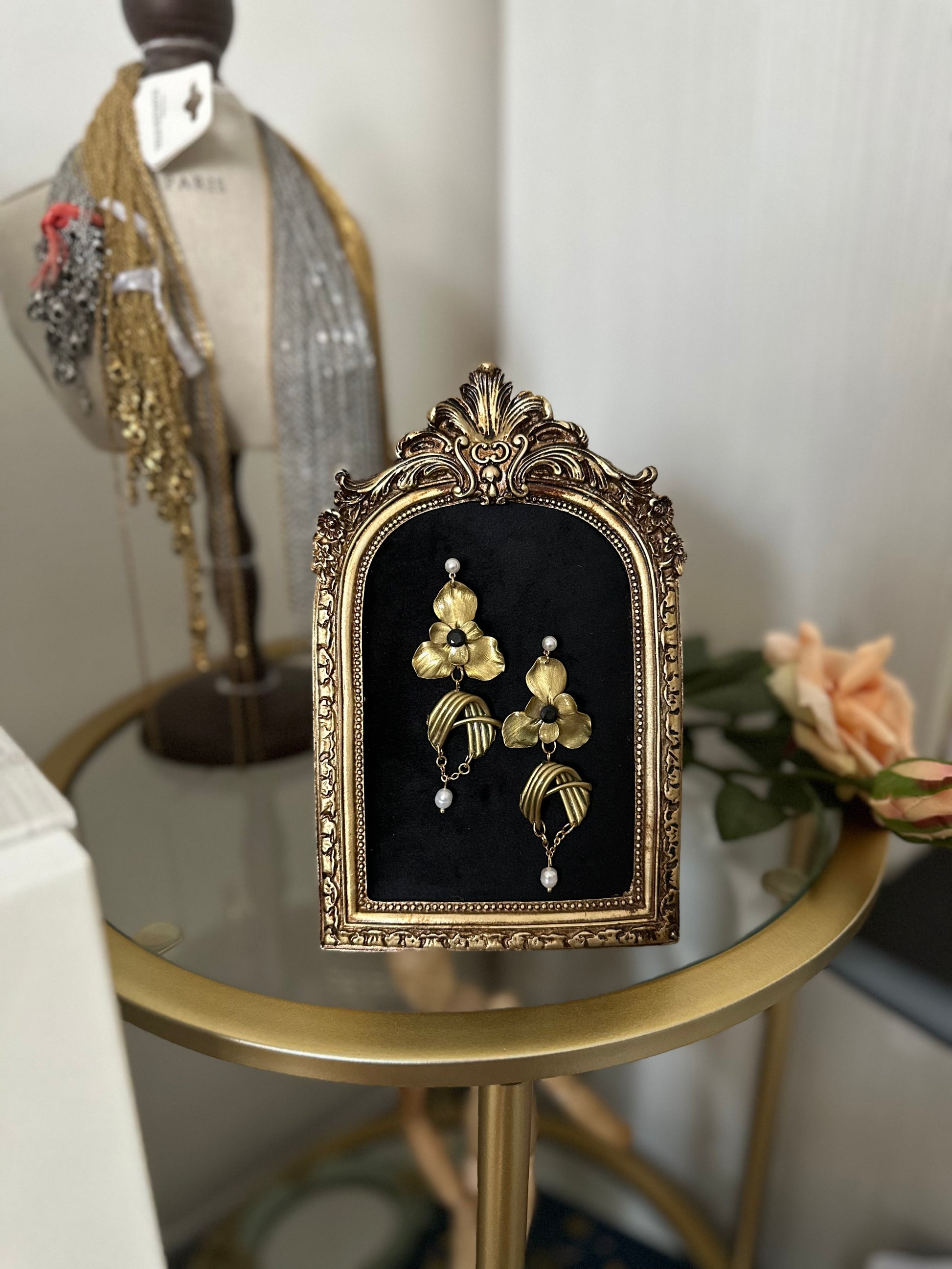 Artistic asymmetrical earrings featuring gold flowers, stainless steel structures and real pearls, photographed on a black velvet background.