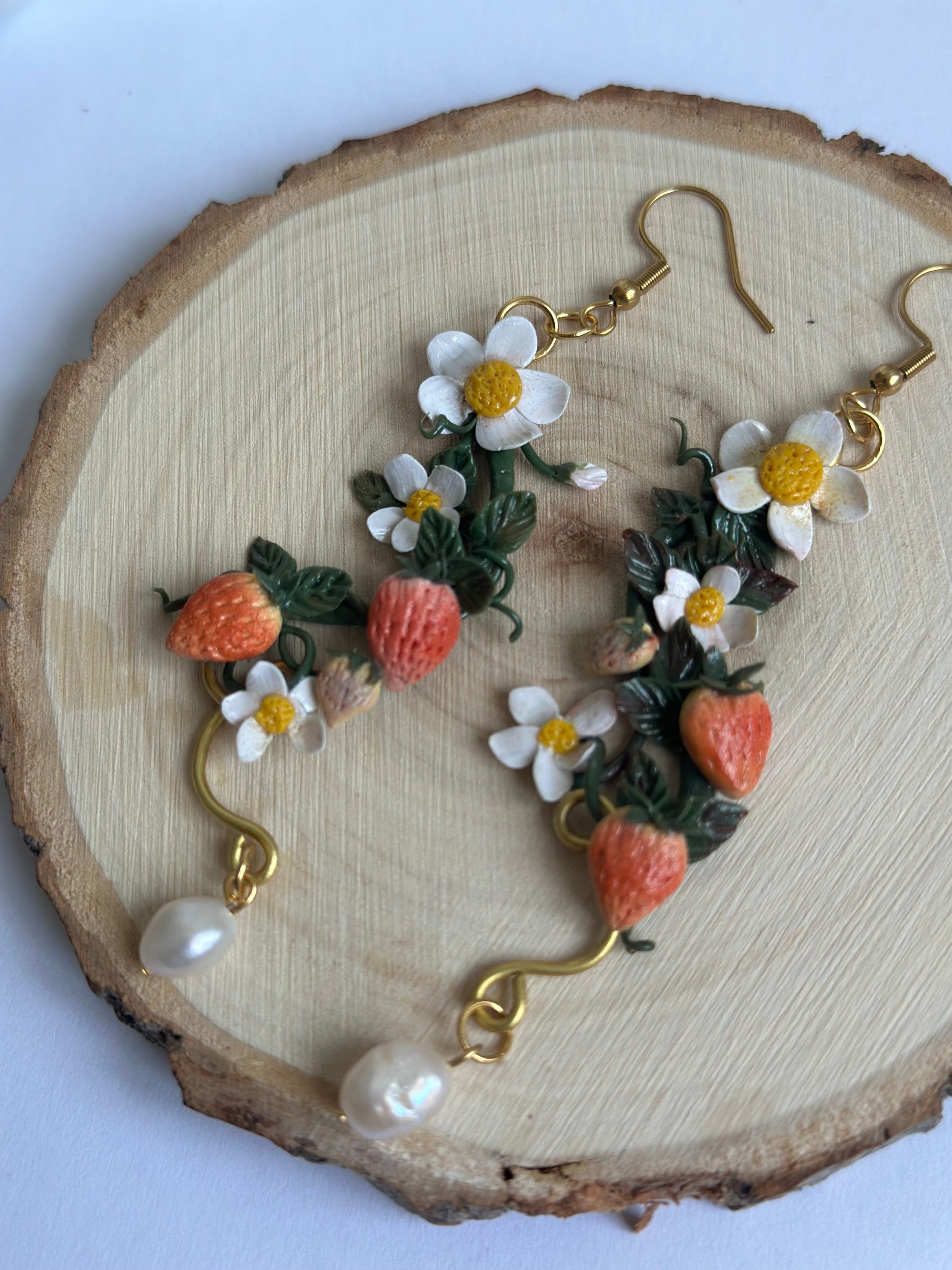 Orecchino artigianale in pasta polimerica con fragole, fiori bianchi, filo dorato e perla. Gioiello botanico romantico.
Handmade polymer clay earring with strawberries, white flowers, gold wire, and pearl. Botanical romantic jewelry.

