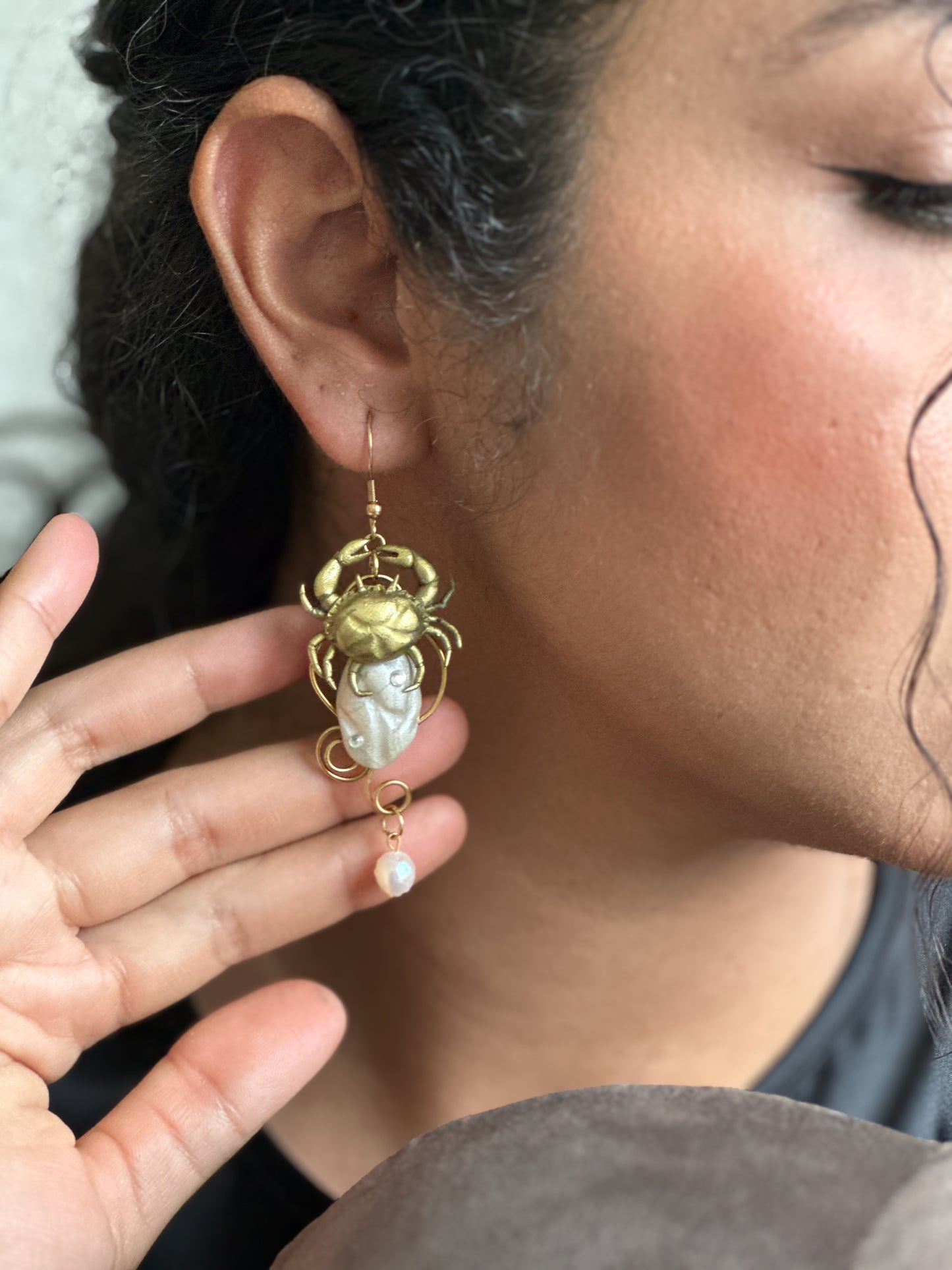     Dramatic yet delicate coastal earrings worn with a black sleeveless dress, turning a basic outfit into something artistic without needing extra styling.