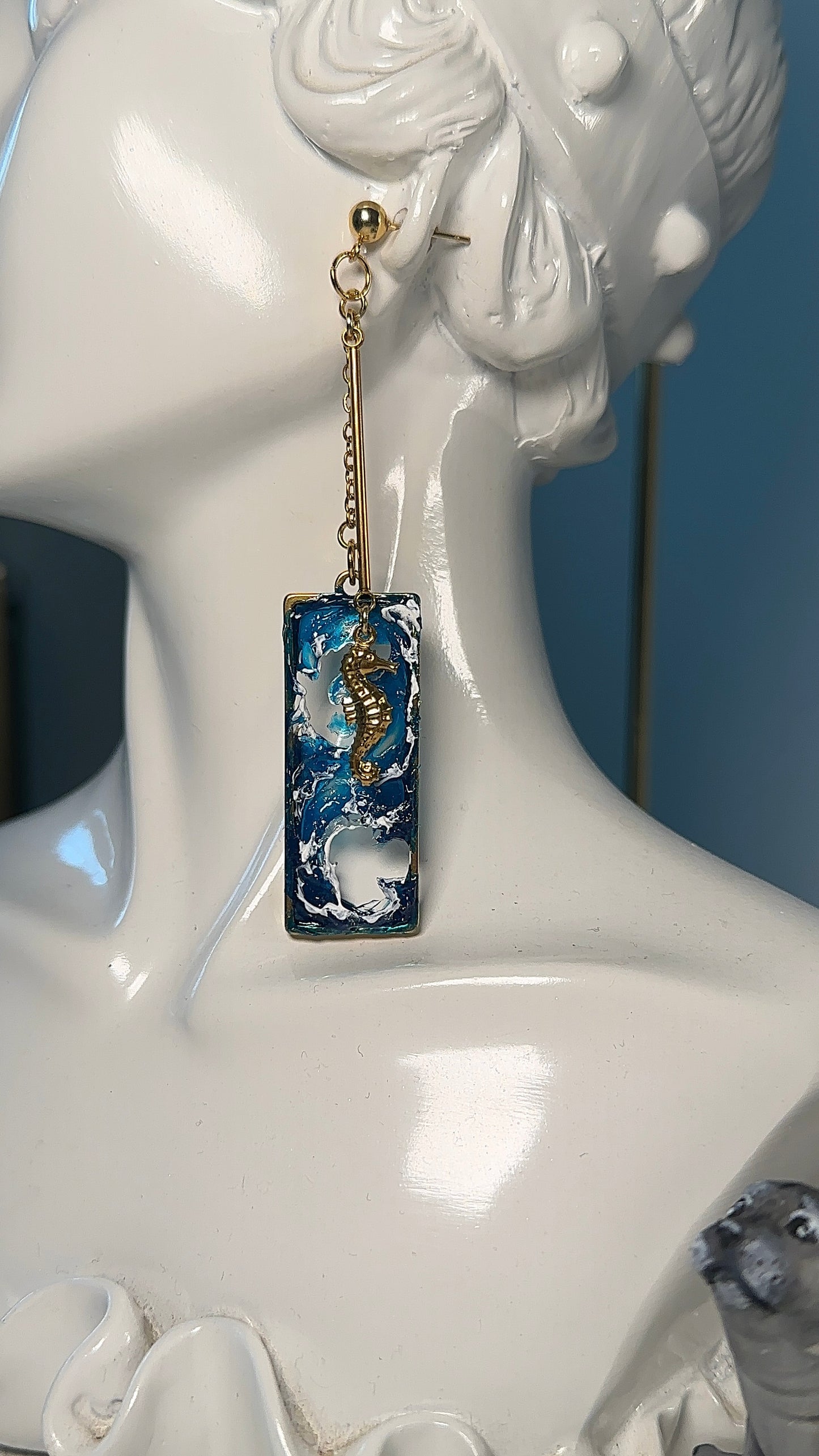 Oltremare earrings styled in a baroque gold frame, showcasing marine beauty and asymmetry