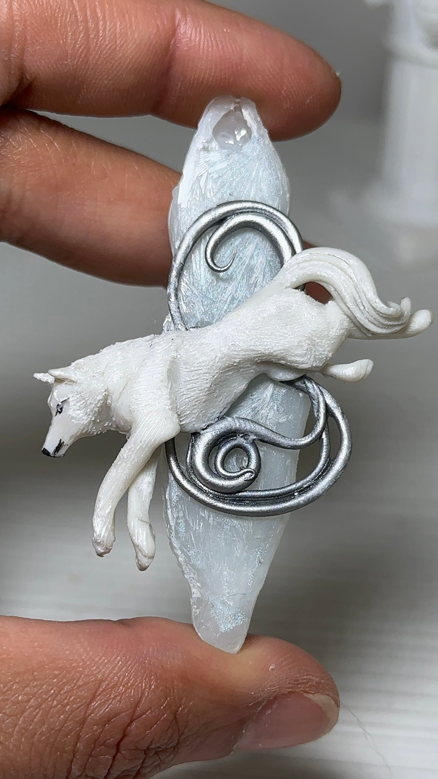 Artisanal winter accessory with a white wolf in mid-leap, crafted in polymer clay and resin for luxury jewelry collectors.