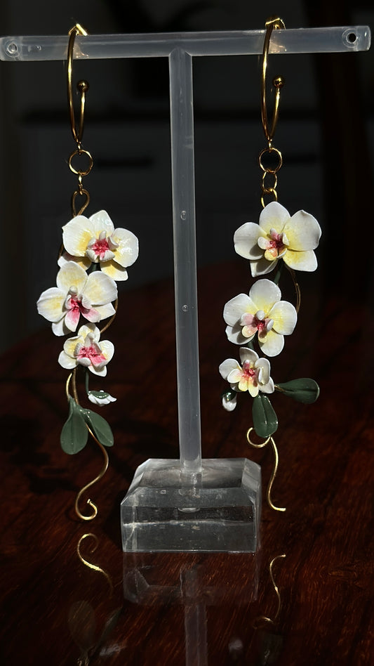 Handmade realistic orchid dangle earrings with ivory flowers, green leaves and gold-tone stainless steel details.