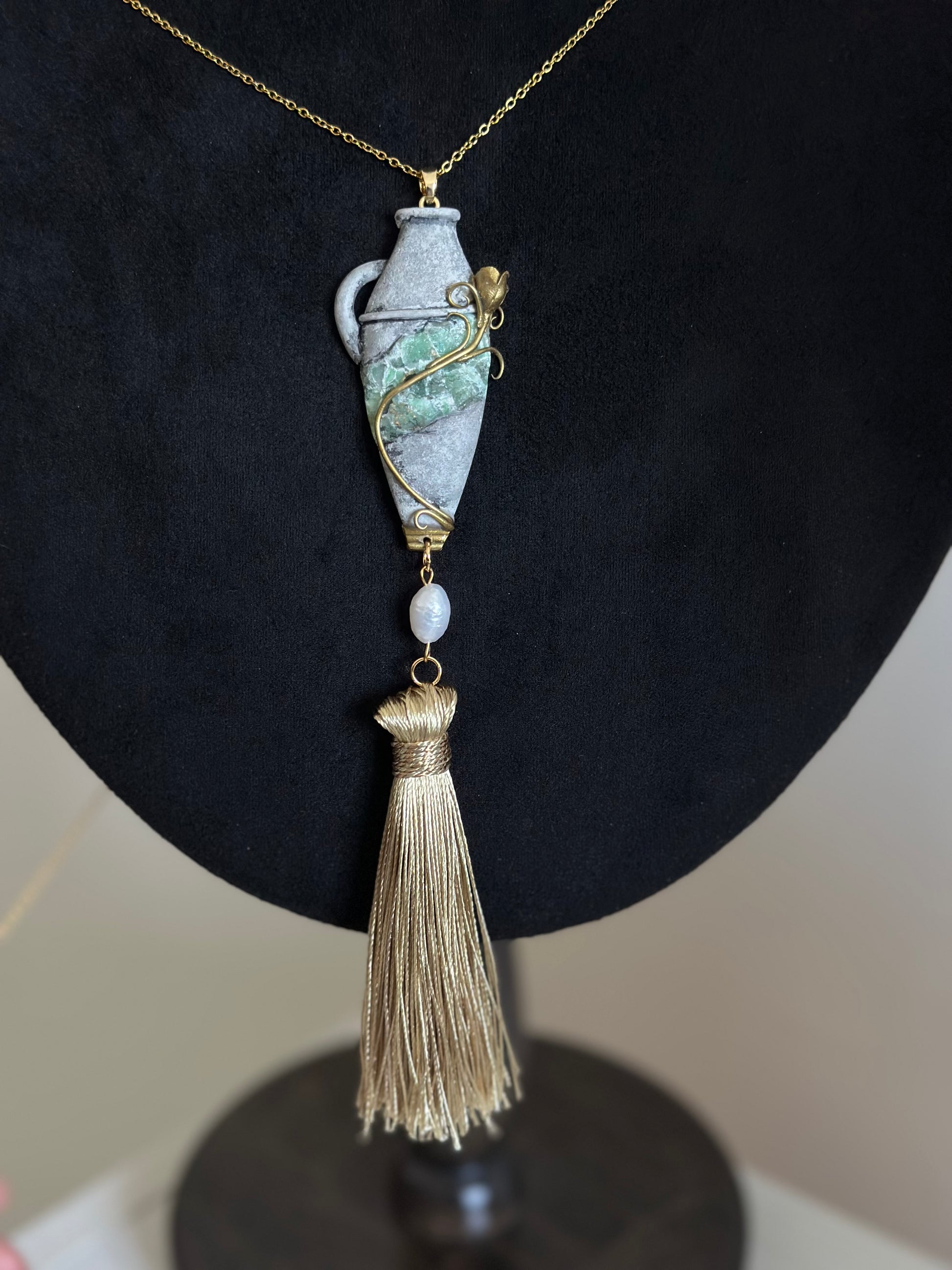     Handmade wearable relic tassel necklace with sculptural vessel pendant, green stone-like center and pearl accent for refined statement outfits.