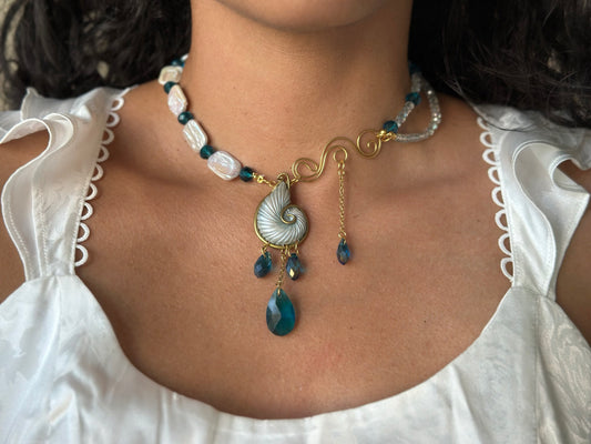 Luxury ocean-inspired necklace with gold nautilus shell and teal crystal drops from Unseen Waters collection.