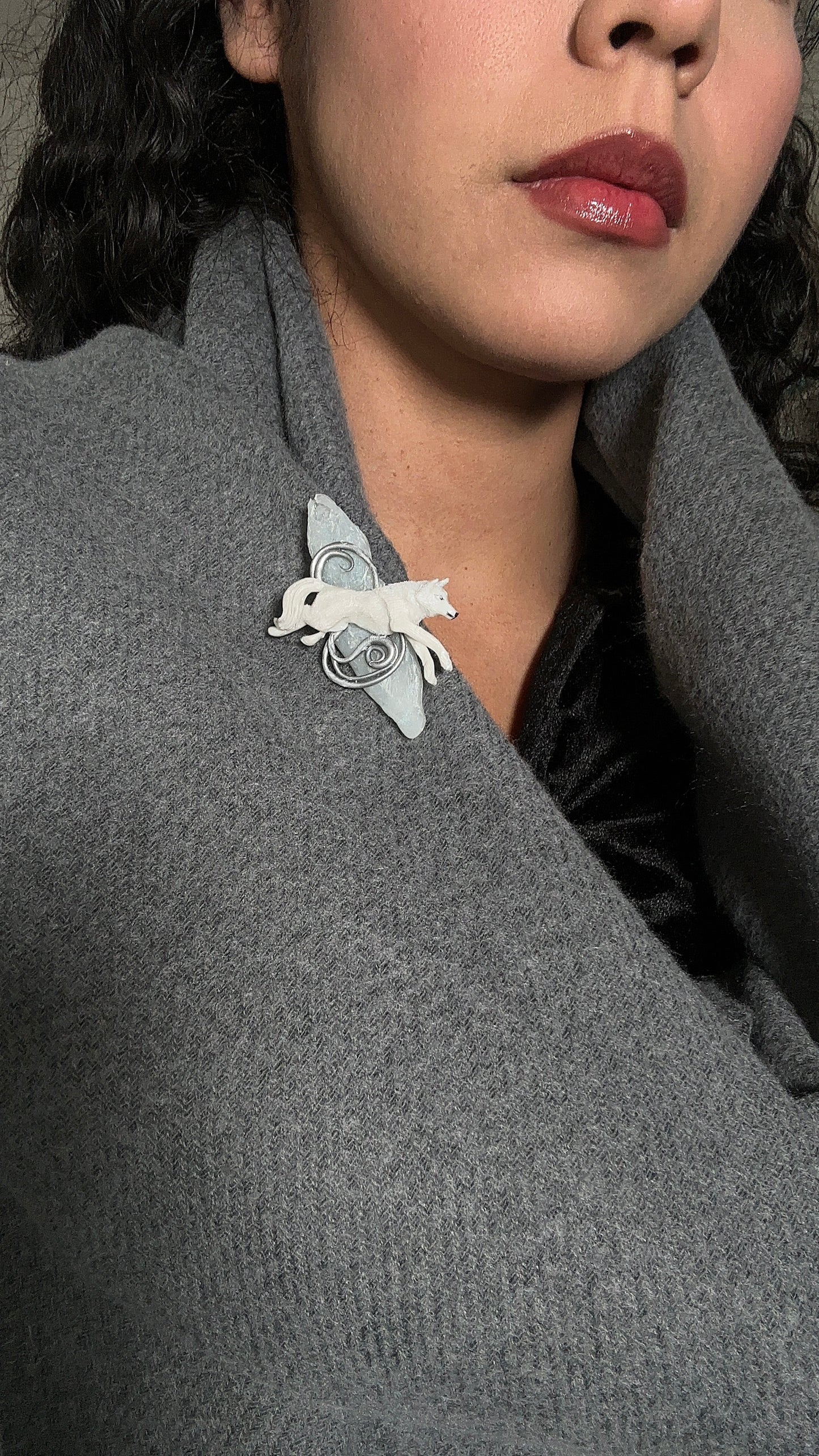 Quiet luxury brooch featuring a sculpted wolf on a frosted resin base, worn as a statement detail on a winter outfit.